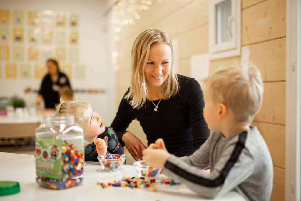 Peikkometsän päiväkotiopettaja opettamassa hamahelmien käyttöä lapselle